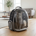 Gray cat sitting inside the bubble window cat carrier backpack in a bright living room